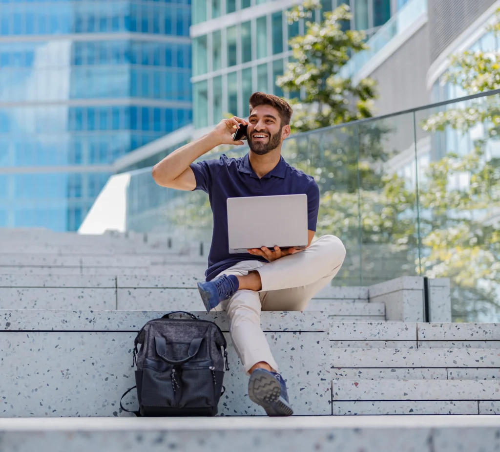 Cyber security student working on a laptop outdoors near an office building
