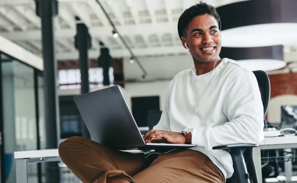 Student smiling while coding on a laptop
